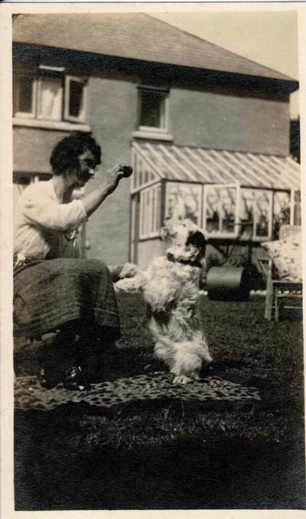 Photograph of Grace Coombe née Loud playing with a dog, around 1930.