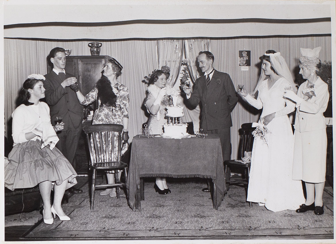 Photograph of Bishopsteignton Players, drinking a toast at the wedding reception in the play 'Orange Blossom'